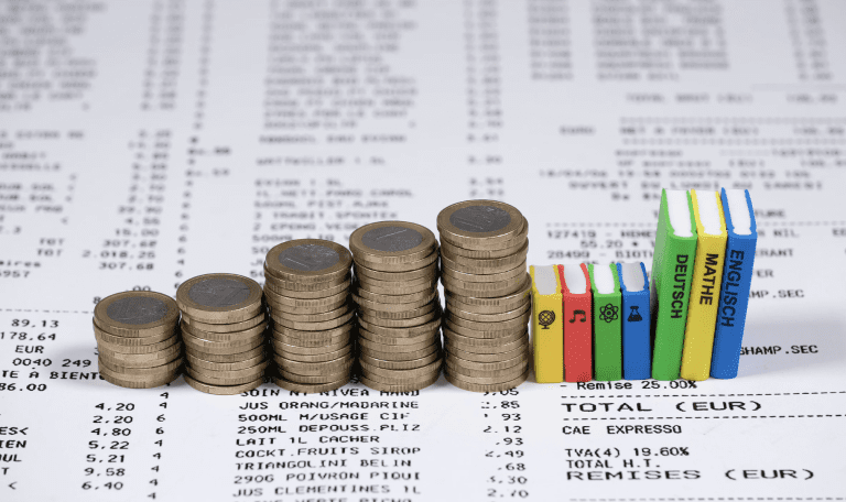 a pile of coins and textboook figurines illustrating the high costs of learning materials